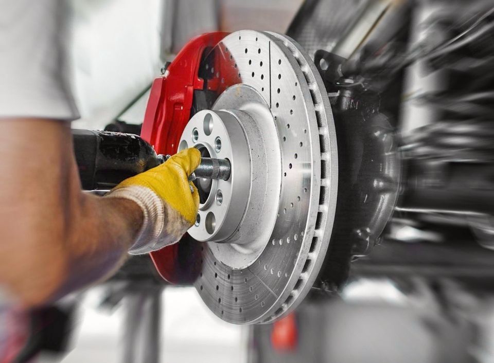 Ein Mann arbeitet an der Bremsscheibe eines Autos und führt technische Wartungsarbeiten durch